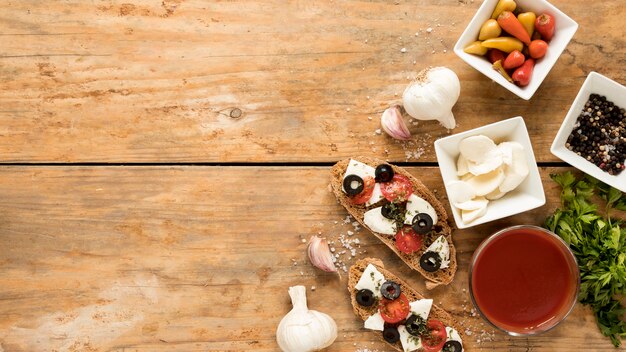 High angle view of bruschetta and ingredient on wooden background