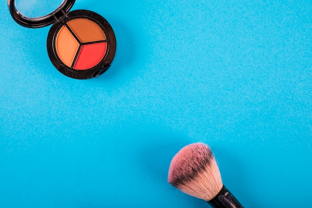 High angle view of brush and blusher on blue background