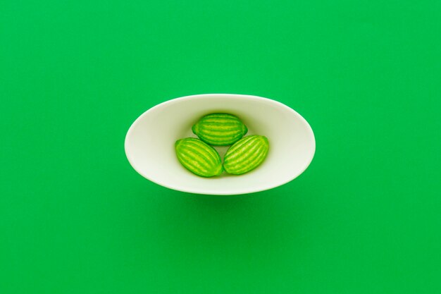 Высокий угол зрения конфеты в миске на зеленом фоне