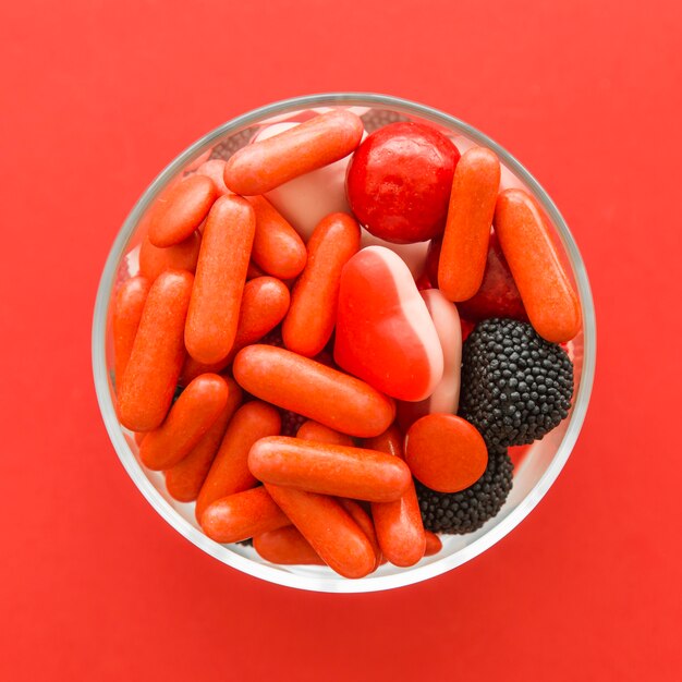 High angle view of carious sweet candies on red background