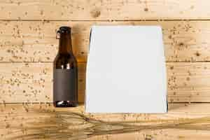 Free photo high angle view of carton box; beer bottle and ears of wheat on wooden plank