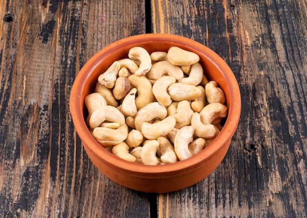 High angle view cashews in pottery on wooden table.