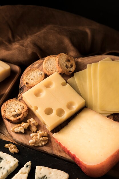 High angle view of cheese; bread slice and walnut on wooden desk