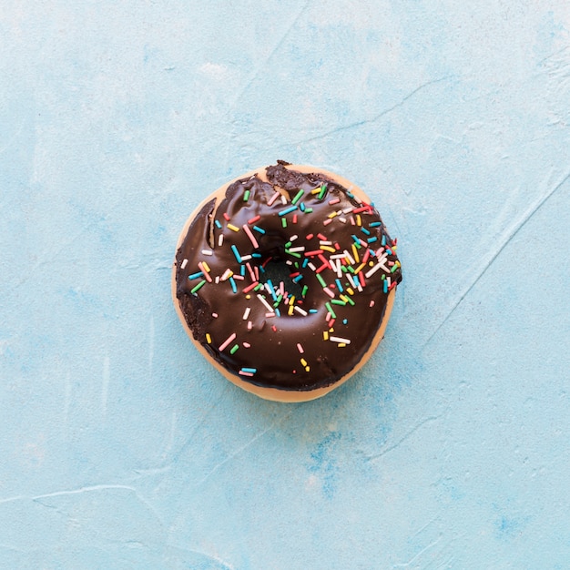 High angle view of chocolate donut on blue backdrop