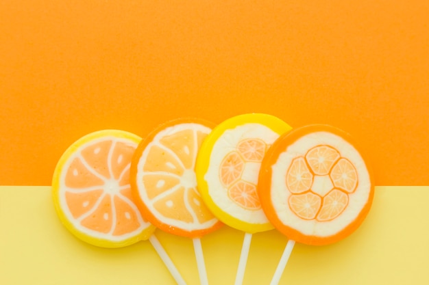 High angle view of citrus fruit candies on yellow and orange background