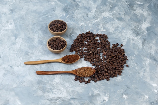 水色の大理石の背景にインスタントコーヒーと木のスプーンでコーヒー粉とボウルの高角度ビューコーヒー豆。水平
