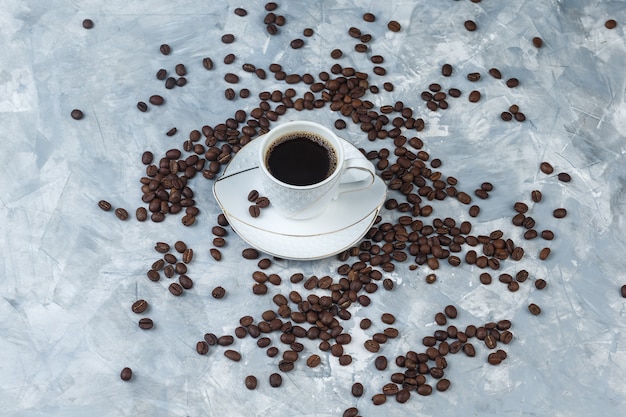 High angle view coffee beans, cup of coffee on light blue marble background. horizontal