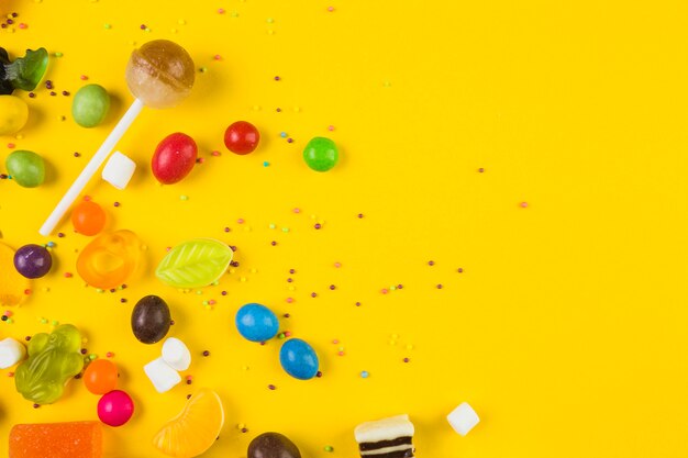 カラフルなキャンディー、キャンデー、黄色の背景にロリポップの高い角度のビュー