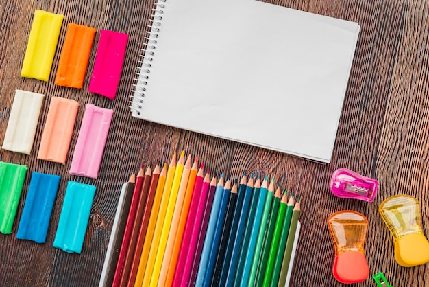 Free photo high angle view of colorful clay and pencil with white spiral notepad