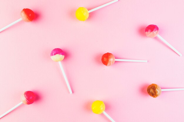 High angle view of colorful lollipops on pink background