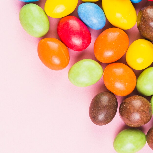 High angle view of colorful sweet candies on pink surface