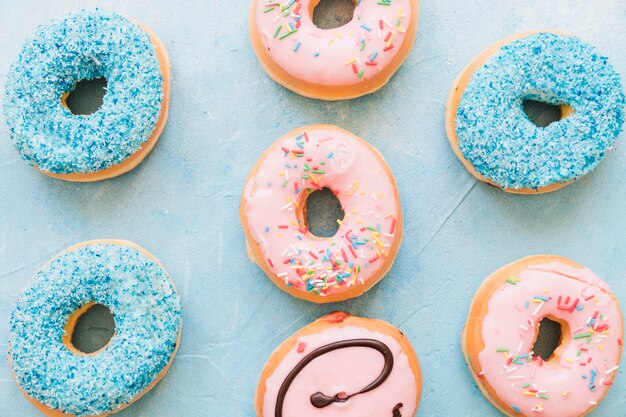 High angle view of colorful tasty donuts on blue backdrop