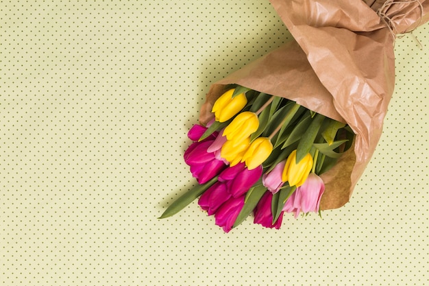 High angle view of colorful tulip flowers over yellow background