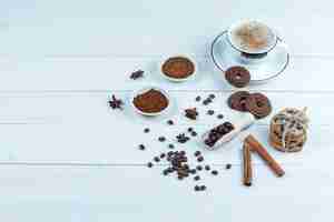 Free photo high angle view cookies, cup of coffee with bowl of instant coffee, coffee beans, cinnamon on white wooden board background. horizontal