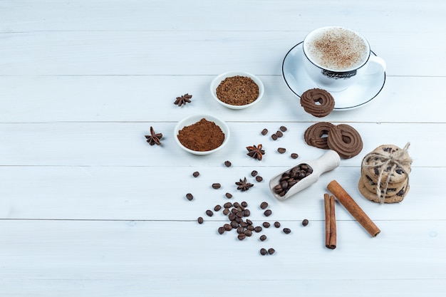 높은 각도보기 쿠키, 인스턴트 커피, 커피 콩, 흰색 나무 보드 배경에 계 피 그릇으로 커피 한잔. 수평