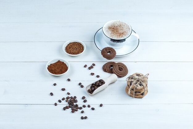 Печенье с высоким углом обзора, чашка кофе с миской растворимого кофе, кофейные зерна на фоне белой деревянной доски. горизонтальный