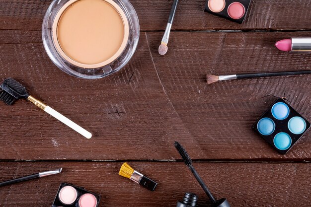 High angle view of cosmetic products with brushes on wooden background