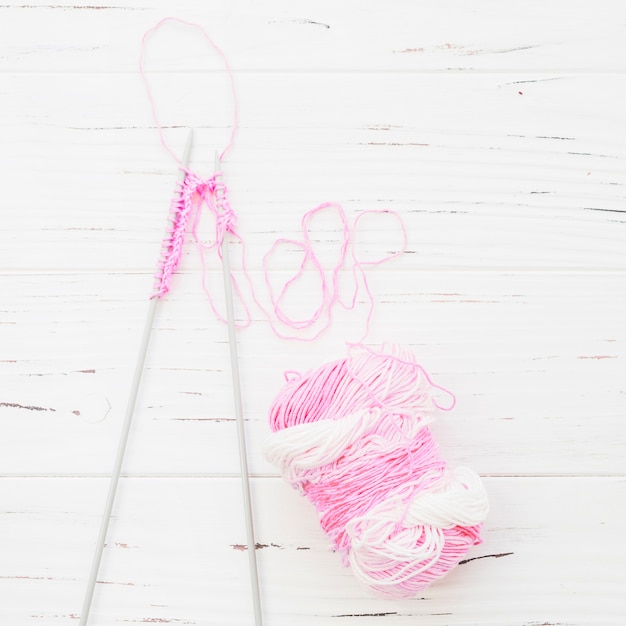 High angle view of crochet with pink yarn on wooden background