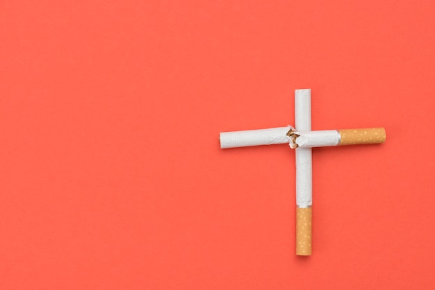 Высокий угол зрения крест знак из сигареты на оранжевом фоне
