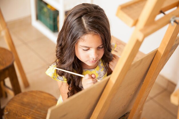 High angle view of a cute little brunette painting during art class