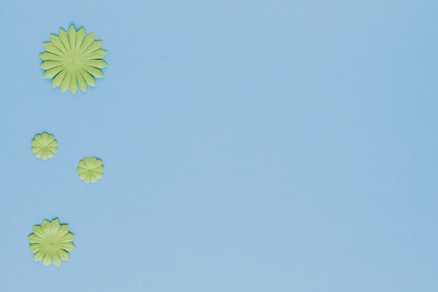 Free Photo high angle view of decorative green flower cutout on blue background