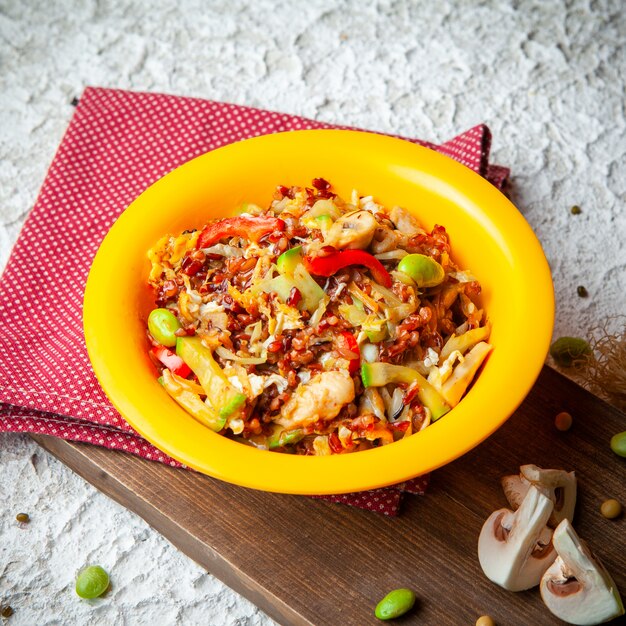 High angle view delicious meal in yellow plate on wood, red cloth and white textured background.