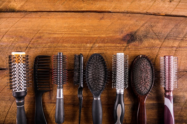 High angle view of different hairbrushes on wooden backdrop