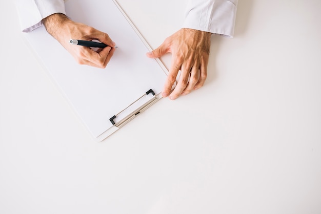 High angle view of doctor hand writing on blank white paper