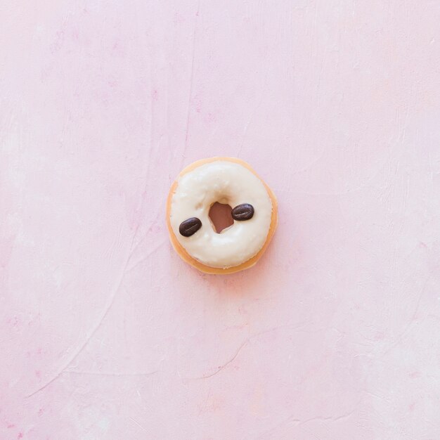 분홍색 배경에 커피 콩으로 장식 된 도넛의 높은 각도보기