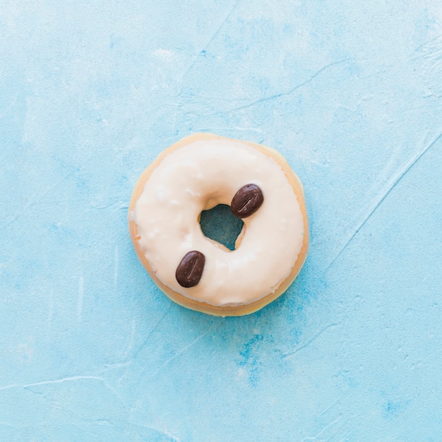 青い背景にコーヒー豆で飾られたドーナツの高い角度の光景
