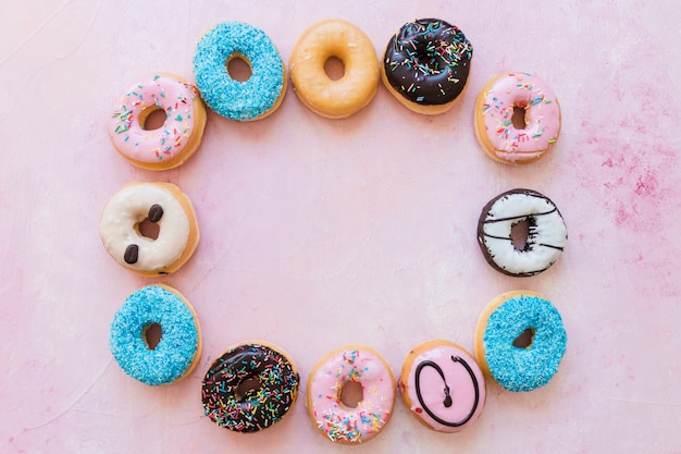 Free photo high angle view of donuts forming frame on pink background