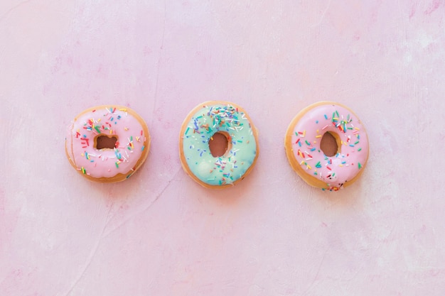 High angle view of donuts with sprinkles on pink background