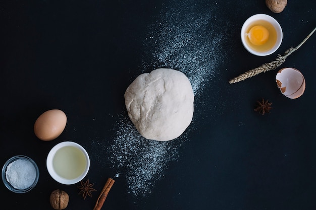 High angle view of dough with baking ingredients on black backdrop