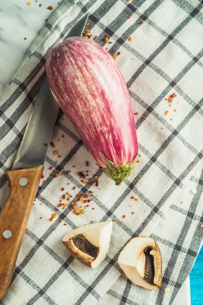 Free photo high angle view of eggplant; mushroom; chili flake and knife on chequered pattern cloth