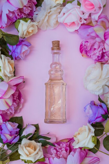 Высокий угол зрения эфирного масла, окруженный свежими цветами на розовом фоне