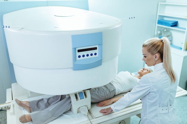 病院での膝MRIスキャン手順中の女性放射線科医と成熟した患者の高角度ビュー