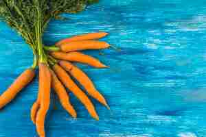 Free photo high angle view of fresh carrots on blue wooden backdrop