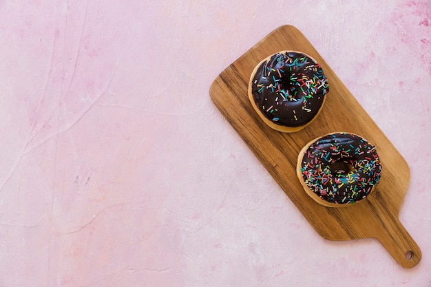 Высокий угол зрения свежих шоколадных пончиков на деревянной разделочной доске