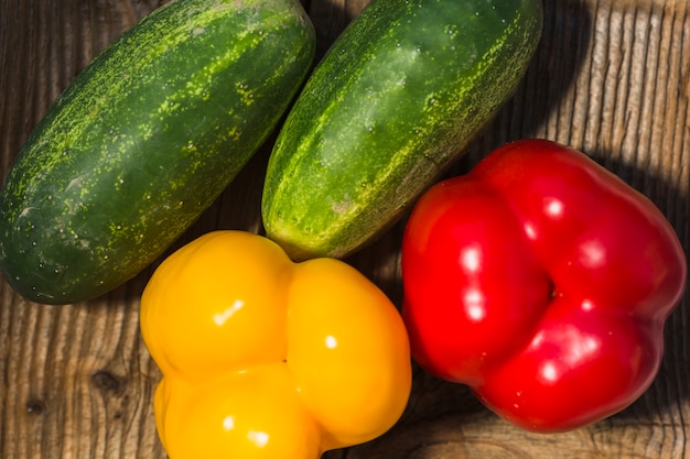 High angle view of fresh cucumbers and colorful bell peppers