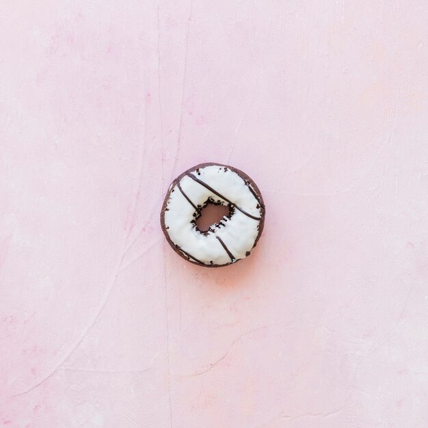 High angle view of fresh donut with icing on pink backdrop