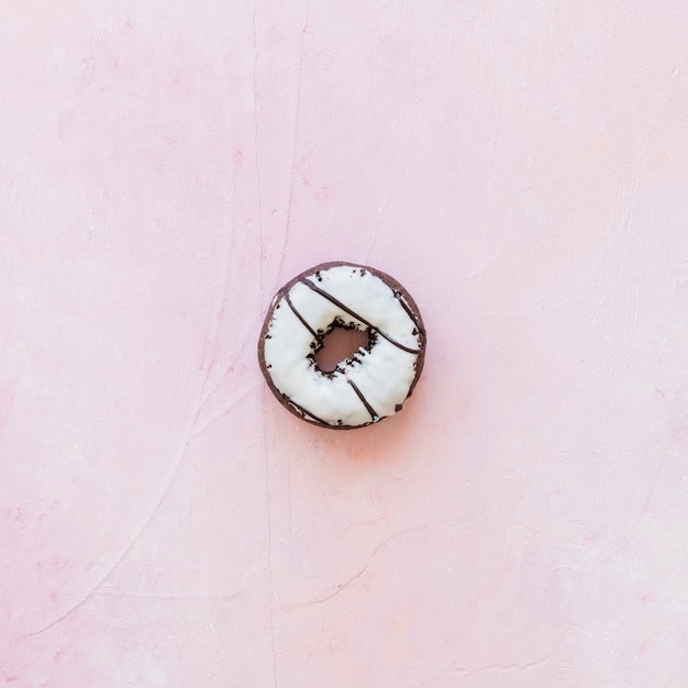 High angle view of fresh donut with icing on pink backdrop