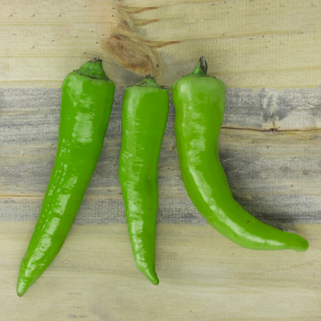 High angle view of fresh green chili peppers on wooden backdrop