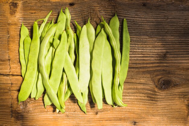 High angle view of fresh green hyacinth beans on wooden backdrop