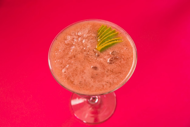 High angle view of fresh juice in martini glass on pink background