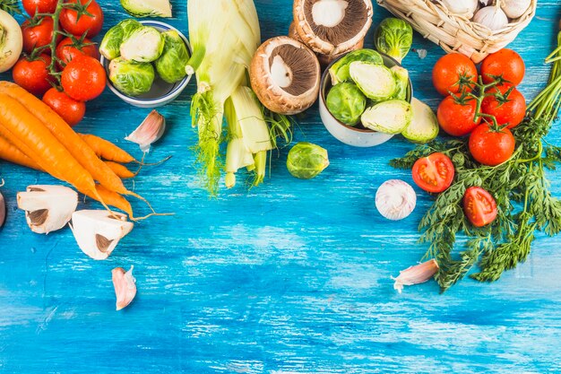 High angle view of fresh organic vegetables on blue wooden backdrop