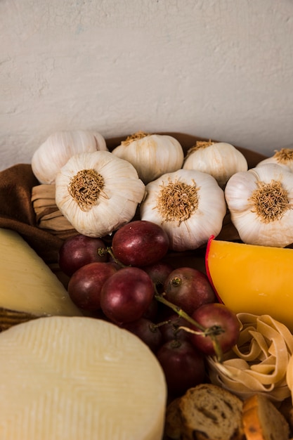 High angle view of garlic; grape; raw pasta and cheese