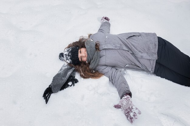 雪に覆われた風景の上に横たわる少女の高角度のビュー