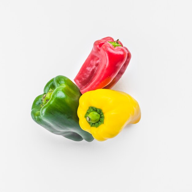 High angle view of green; yellow and red bell peppers on white background