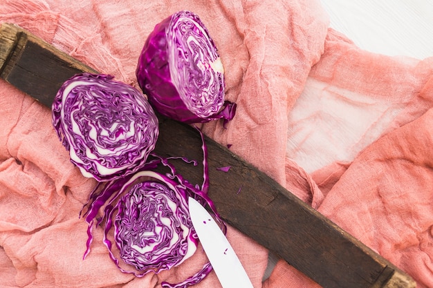 High angle view of halved fresh purple cabbage and knife on textile