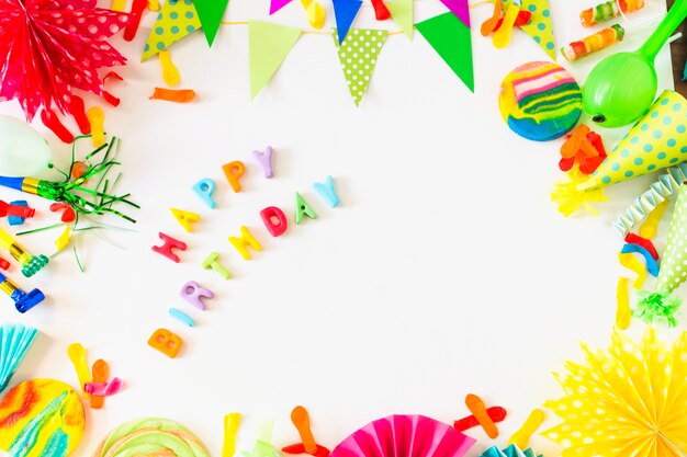 High angle view of happy birthday text with party accessories on white backdrop